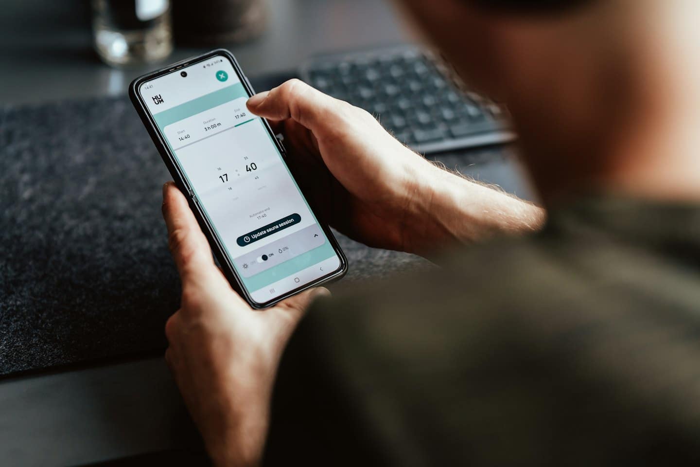 Hands using a smartphone app to book a sauna session.